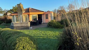 A modern house with a patio, stone walls, and a well-maintained lawn. - 3 bedroom accommodation in Julianadorp aan Zee (Julianadorp aan Zee)
