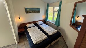 A bedroom with two beds, a window with curtains, a painting on the wall, and a mirror on the right. - 3 bedroom accommodation in Julianadorp aan Zee (Julianadorp aan Zee)