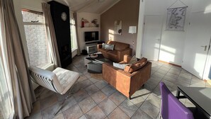 A living room with a fireplace, a sofa, a coffee table, and a television. - 3 bedroom accommodation in Julianadorp aan Zee (Julianadorp aan Zee)