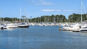 Een jachthaven met diverse boten afgemeerd, kalm water en een heldere lucht.