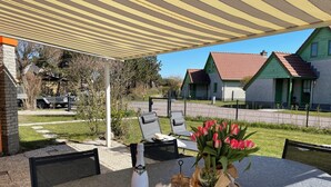 Eine Terrasse im Freien mit einem Tisch für zwei Personen, einer Weinflasche und einem Blumenstrauß.