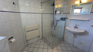 Ein Badezimmer mit einer Duschkabine, einem weißen Waschbecken und einer Toilette.