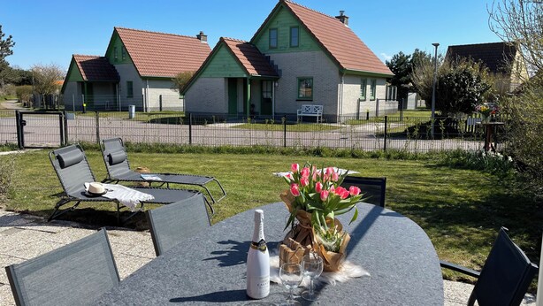 Eine Terrasse mit Sitzgelegenheit und einem Tisch, gedeckt mit einer Champagnerflasche und Gläsern.
