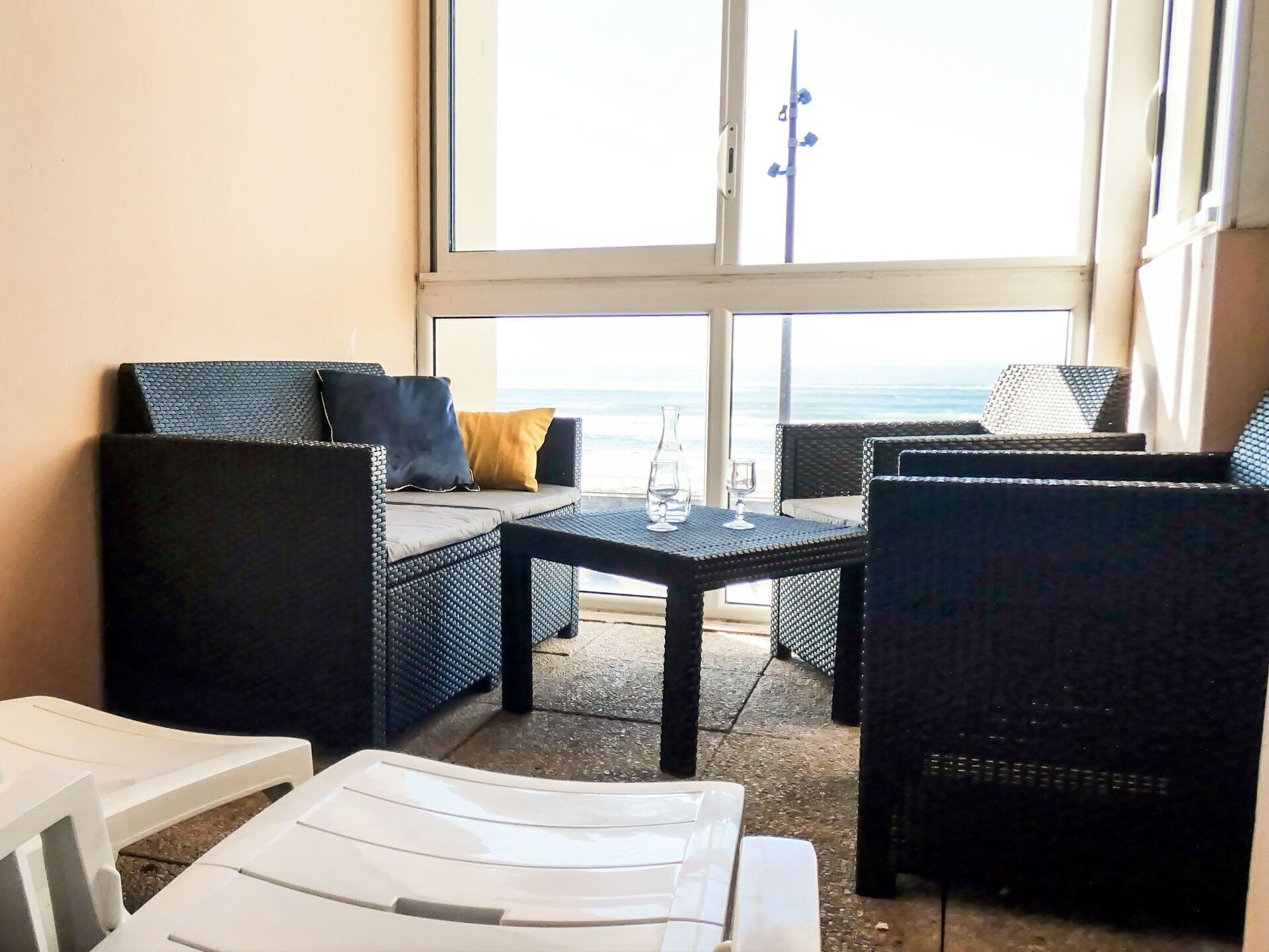 A balcony with wicker furniture, a table, and a view of the ocean.