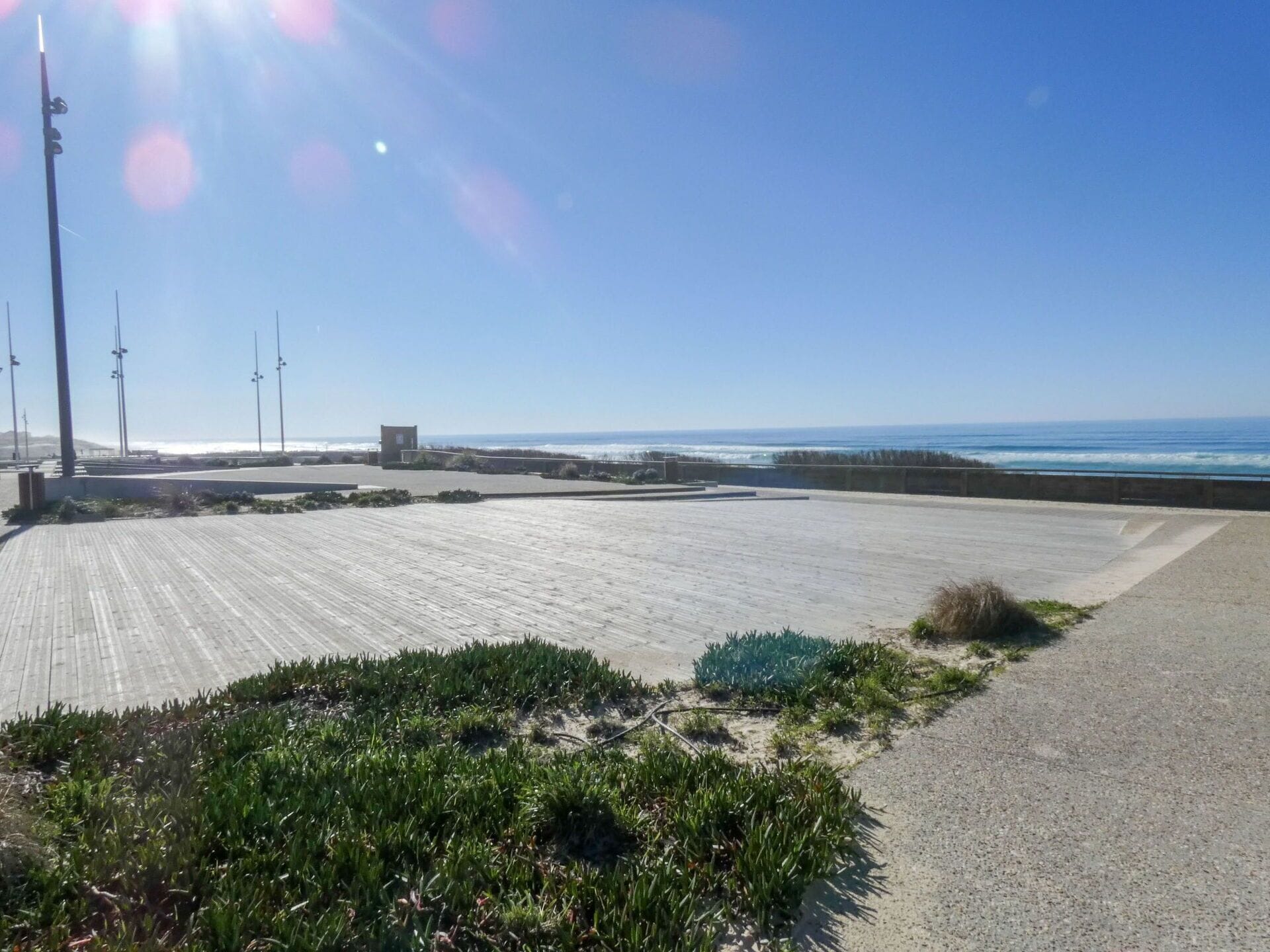 Une promenade en bord de mer offrant une vue sur l’océan, un petit bâtiment et une zone herbeuse.