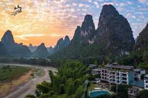 Un hotel de varios pisos, rodeado de abundante vegetación y montañas.