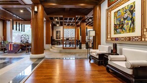 A spacious lobby with wooden flooring, a reception desk, seating area, and a staircase leading to upper floors. - Yangshuo Mountain River Ballad Hotel (Guilin)