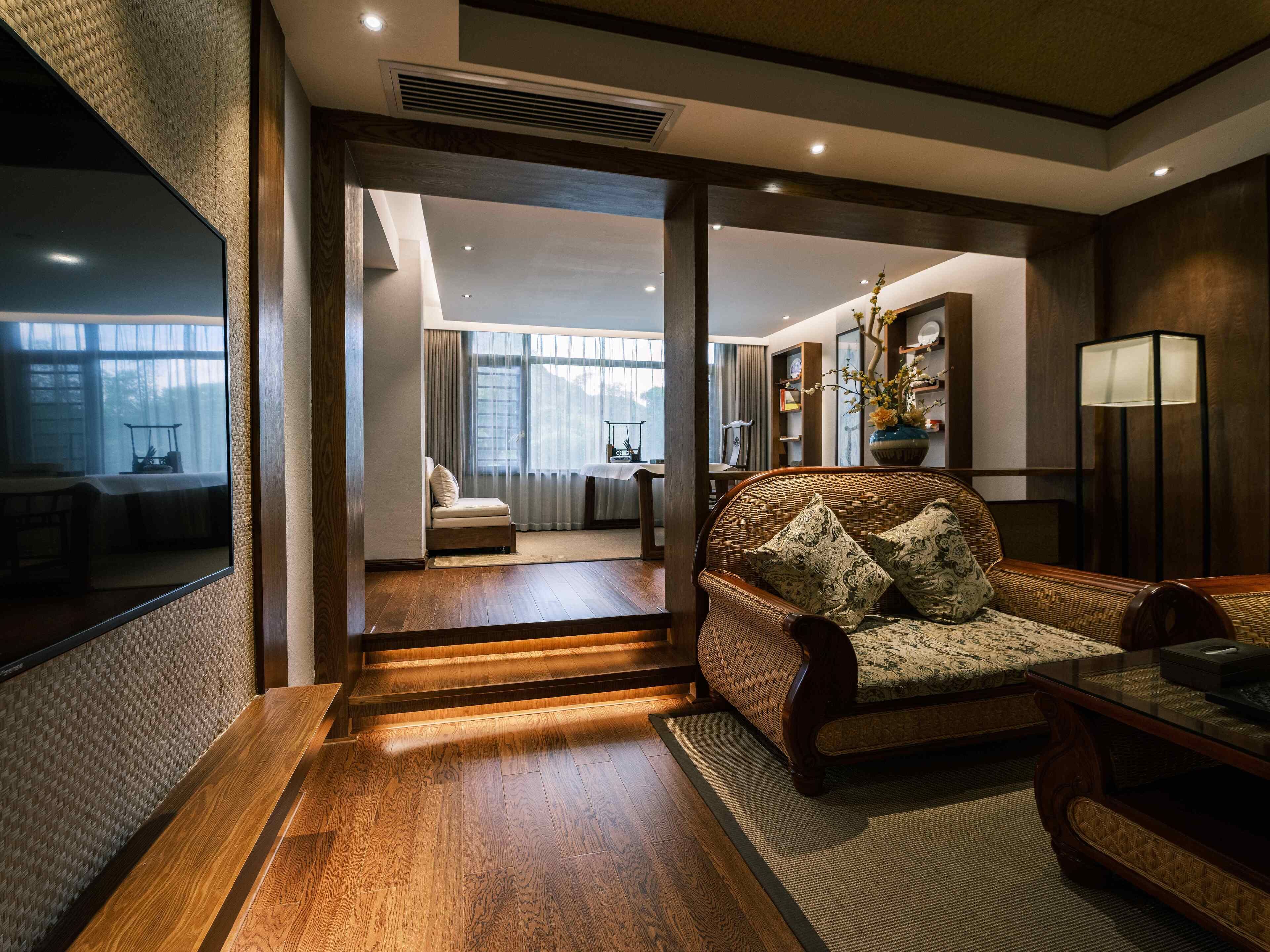 A modern living room with a sofa, a dining area, and a staircase leading to another room.