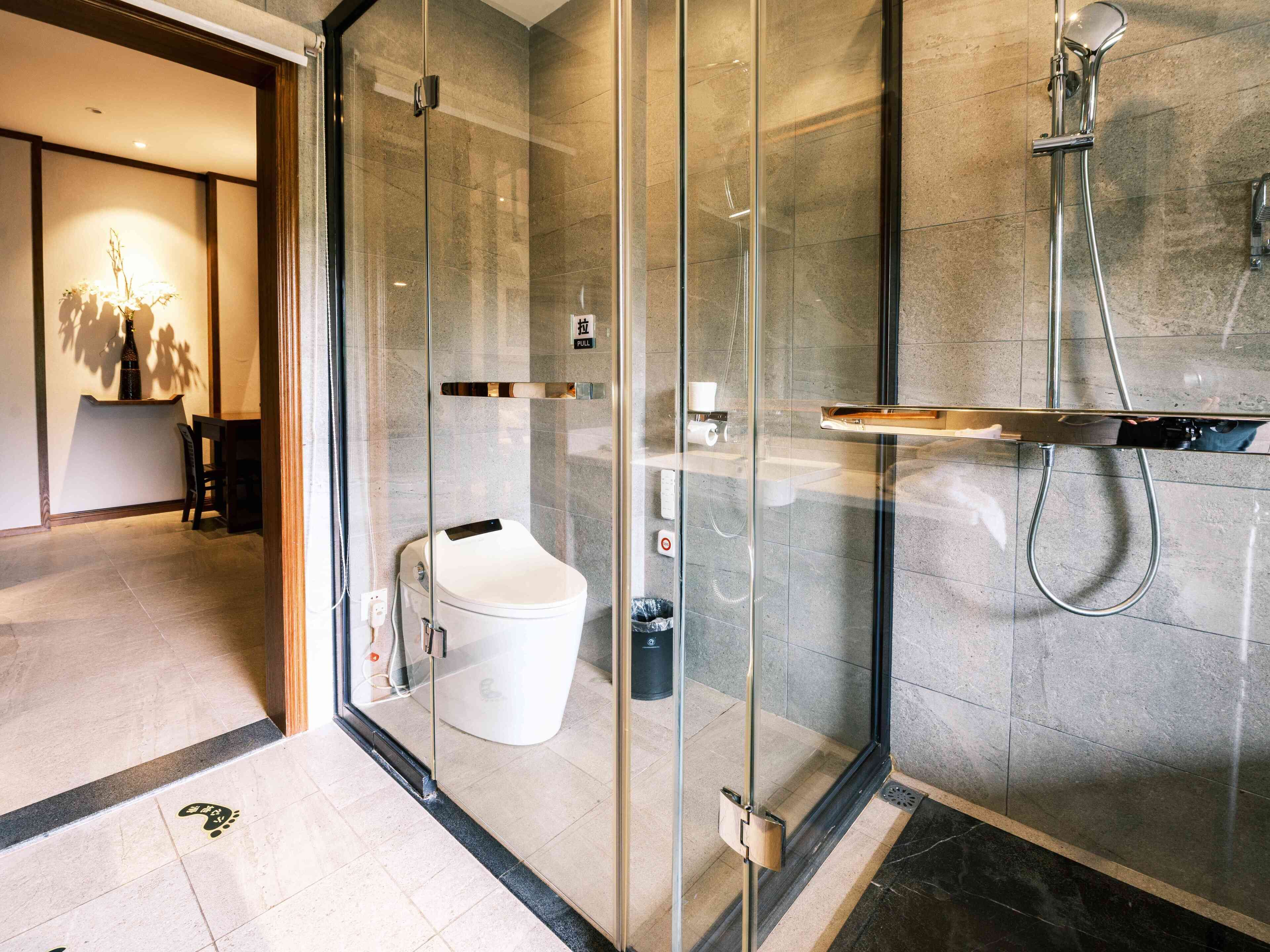 A modern bathroom with a glass shower enclosure, a toilet, and a sink.