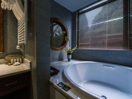 Un baño moderno con una bañera independiente, un tocador con espejo y una ventana con persianas.