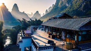 A traditional building with a tiled roof and a balcony overlooking a valley. - Yangshuo Mountain River Ballad Hotel (Guilin)