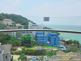 Un hotel frente al mar, con vistas al océano, rodeado de vegetación y edificios residenciales.
