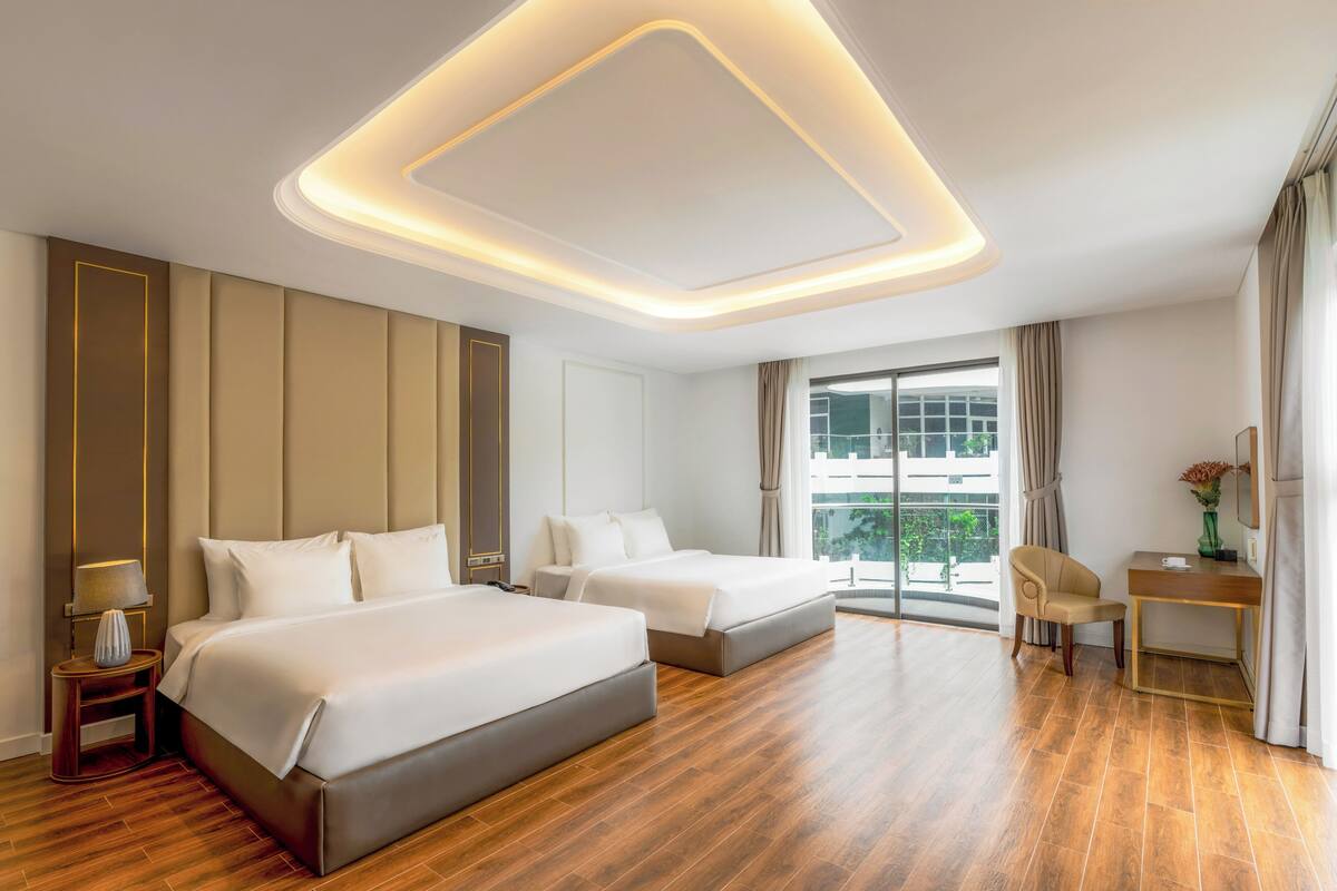 Une chambre d’hôtel avec deux lits, un bureau et une grande fenêtre.