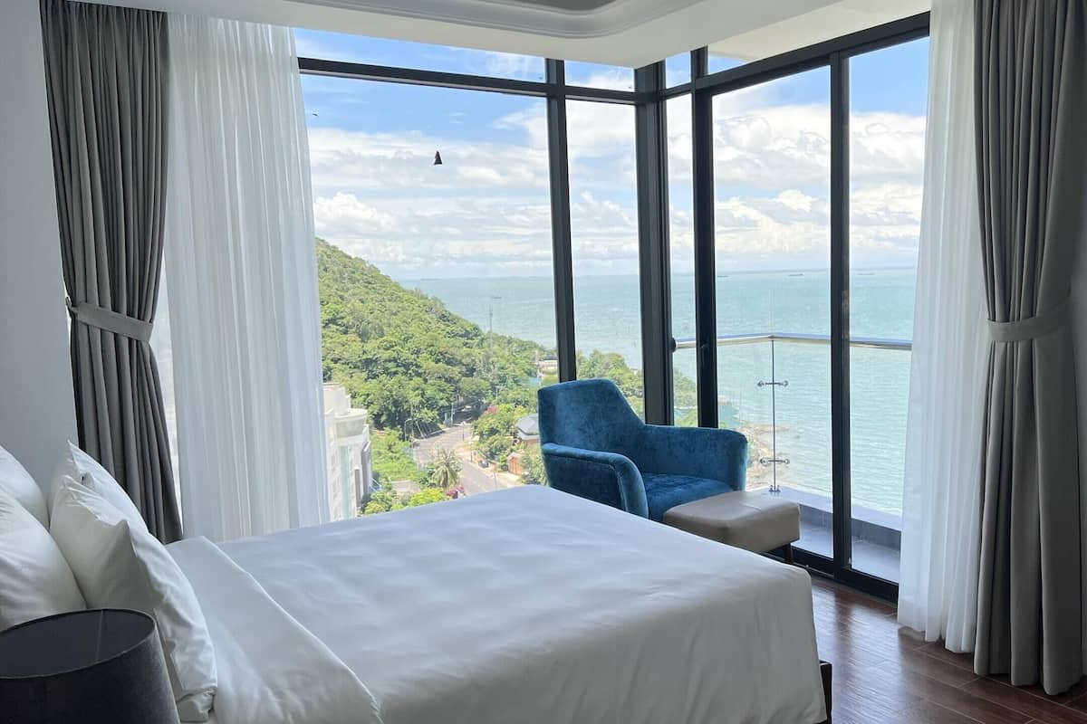 Une chambre dotée d’une grande fenêtre donnant sur un paysage côtier.