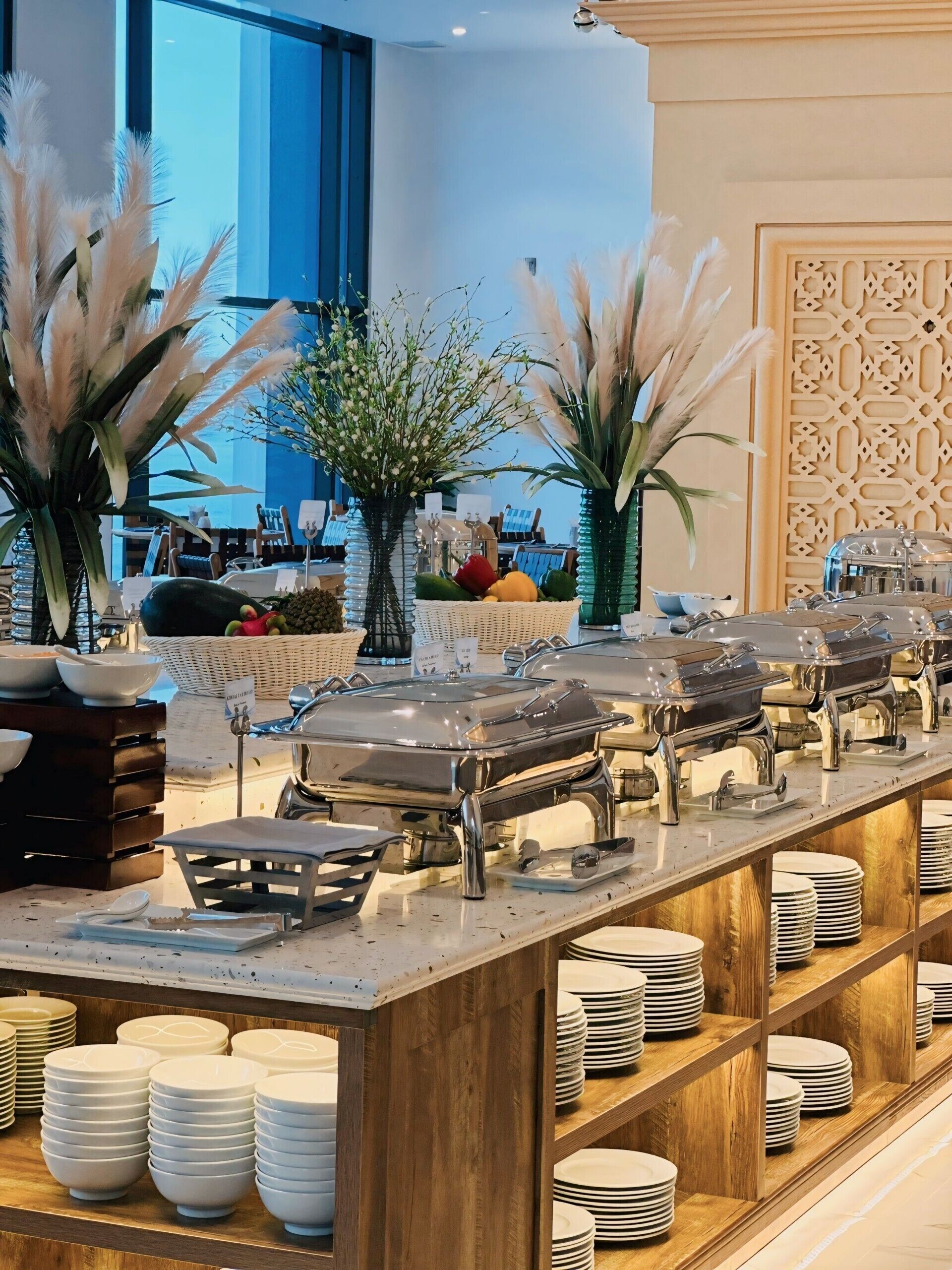 Ein reichhaltiges Buffet mit mehreren Speiseauslagen, einer Auswahl an Gerichten und einer dekorativen Pflanzengestaltung.