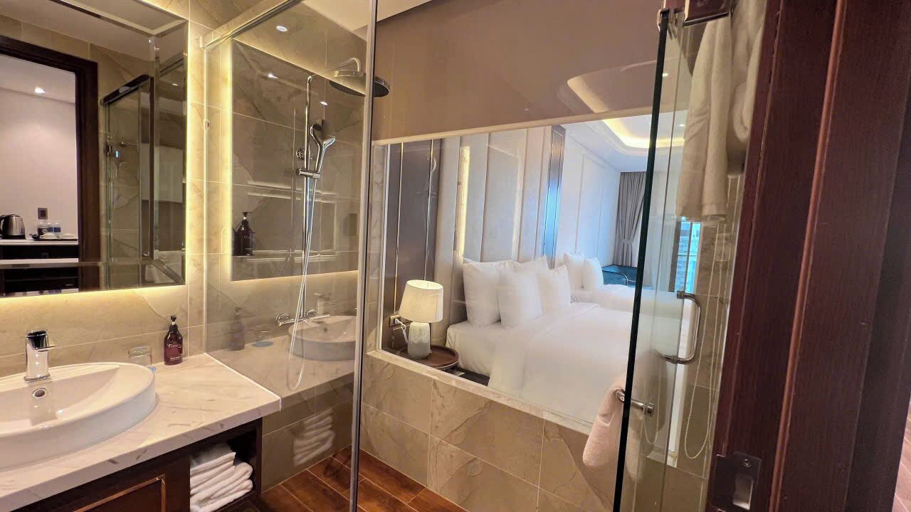 A modern bathroom with a glass-enclosed shower, a large mirror, and a white sink.