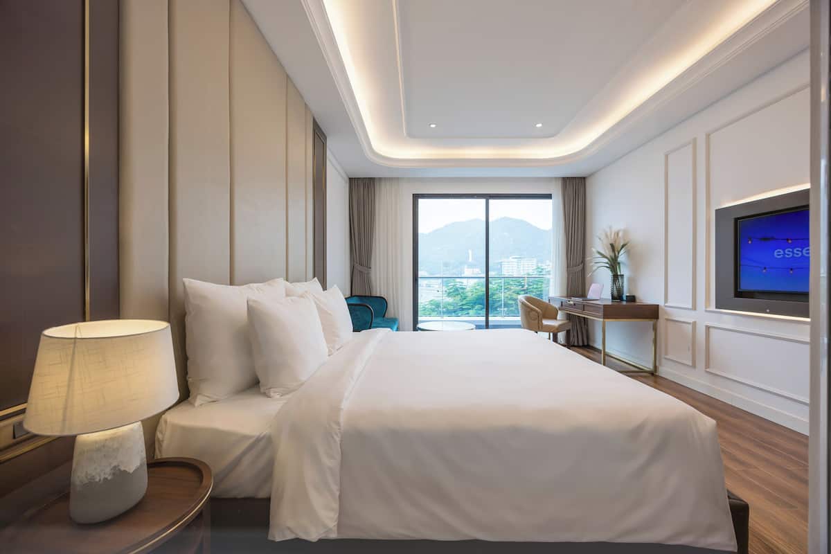 Une chambre d’hôtel avec un lit, un bureau, une chaise, une télévision et une vue sur la ville.