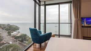Een hotelkamer met een groot raam, een bed, een blauwe stoel en een televisie.
