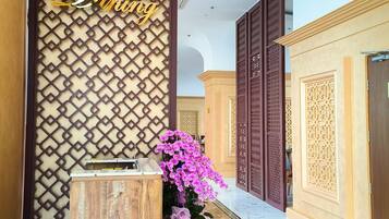 A reception area with a wooden desk, a potted orchid, and a decorative wall with a geometric pattern.