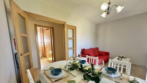 Un coin repas avec une table ronde dressée pour quatre personnes, agrémentée de bols bleus, de verres à vin et d'un centre de table composé de verdure.