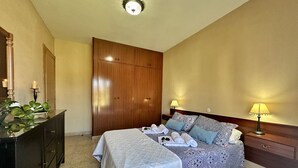 Hotellihuone, jossa on kaksi sänkyä, puinen vaatekaappi, lipasto ja kaksi yöpöytävalaisinta.