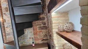 A spiral staircase with a stone wall background and wooden steps. - B&B Sotto le Mura Wellness (Pietramontecorvino)