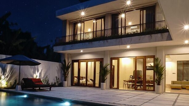 A modern two-story house with a swimming pool, outdoor seating, and a well-lit balcony. - Kanaka Villa Buahan (Payangan)