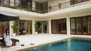 A two-story building with a swimming pool, large windows, and a balcony with plants. - Kanaka Villa Buahan (Payangan)