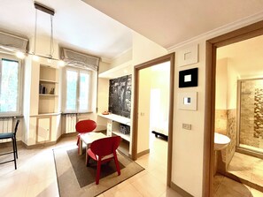 Una cocina moderna con comedor, una silla roja y vista al dormitorio contiguo.