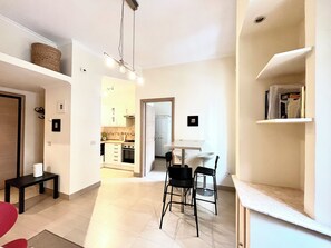 Una cocina moderna con armarios blancos, un comedor con dos sillas y una pequeña mesa.