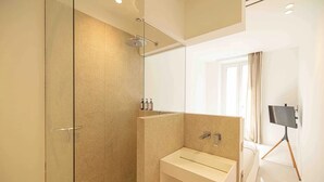 Ein modernes Badezimmer mit einer Duschkabine aus Glas, einem Waschbecken mit Spiegel und einer auf einem Stativ befestigten Kamera.