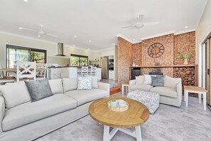 A modern living room with a sectional sofa, a coffee table, and a fireplace with a brick wall.