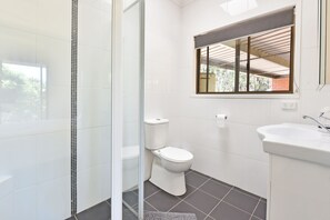 A bathroom with a toilet, a sink, and a shower area.