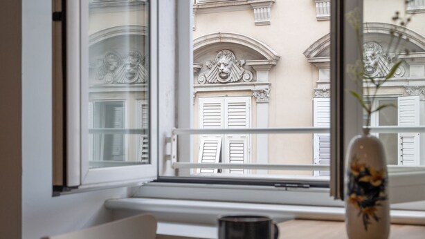 A view from a window with a table, a chair, and a vase with flowers. - La Casa in Viale, short term rent apartment (Trieste)