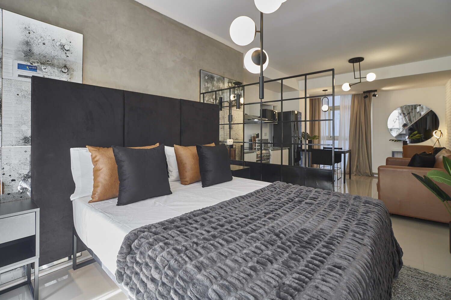A modern bedroom with a large bed, a desk, and a mirror.