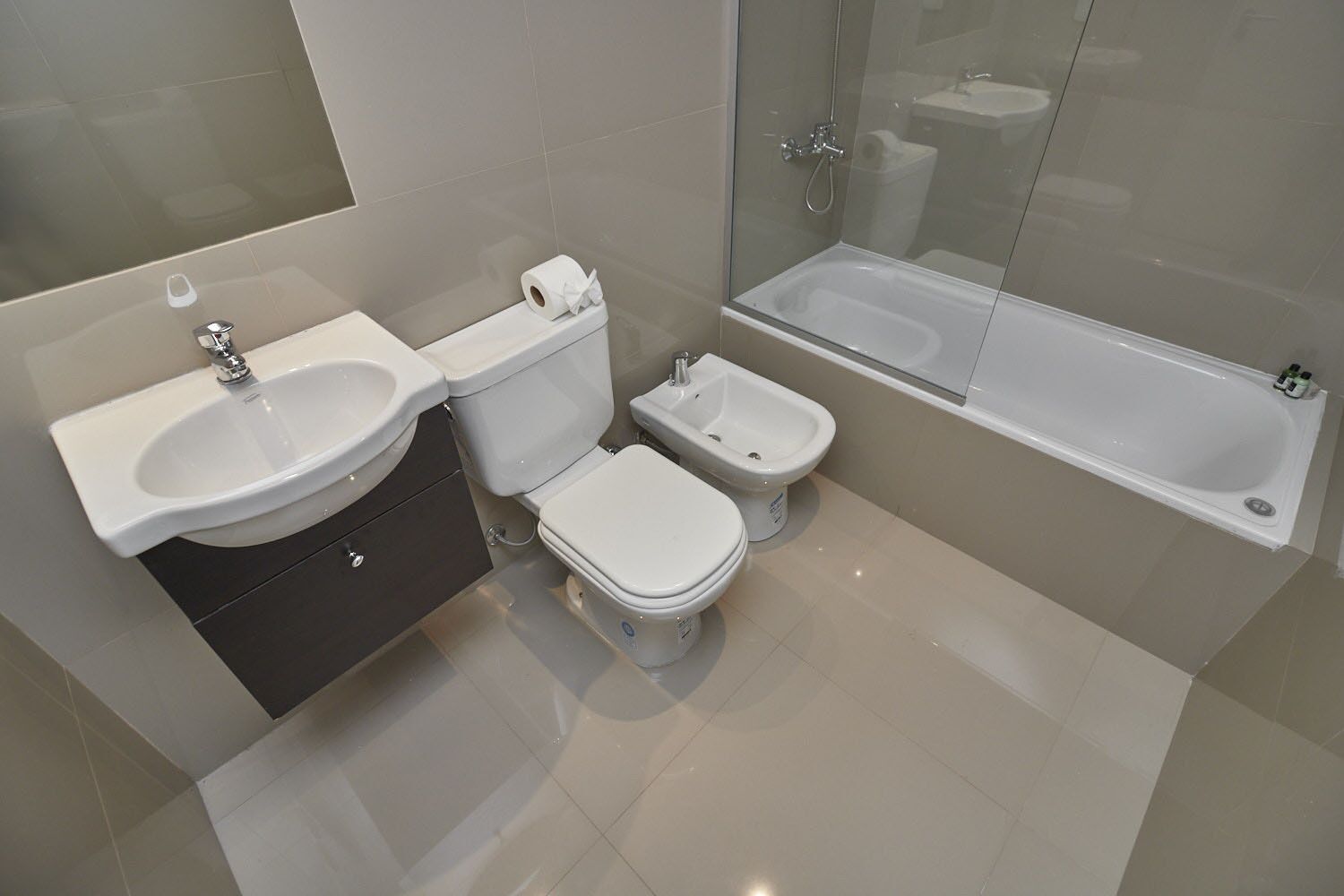 Une salle de bain moderne équipée d’un lavabo, de deux toilettes, d’un bidet et d’une baignoire.
