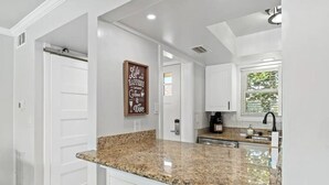 A kitchen with white cabinets, a granite countertop, and a coffee machine.