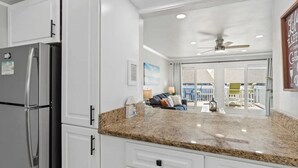 A kitchen with white cabinets, a granite countertop, and a refrigerator.