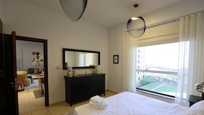 Une chambre d’hôtel avec un lit, une commode, un miroir et une fenêtre donnant sur des immeubles.