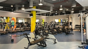 Une salle de sport équipée de tapis de course, de vélos elliptiques et de matériel de musculation.