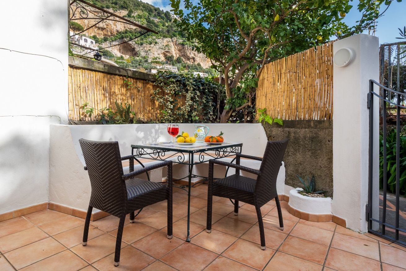 A patio with a table and chairs, a small plant, and a view of a hillside.