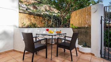 Un patio con una mesa y sillas, una planta pequeña y vistas a una colina.