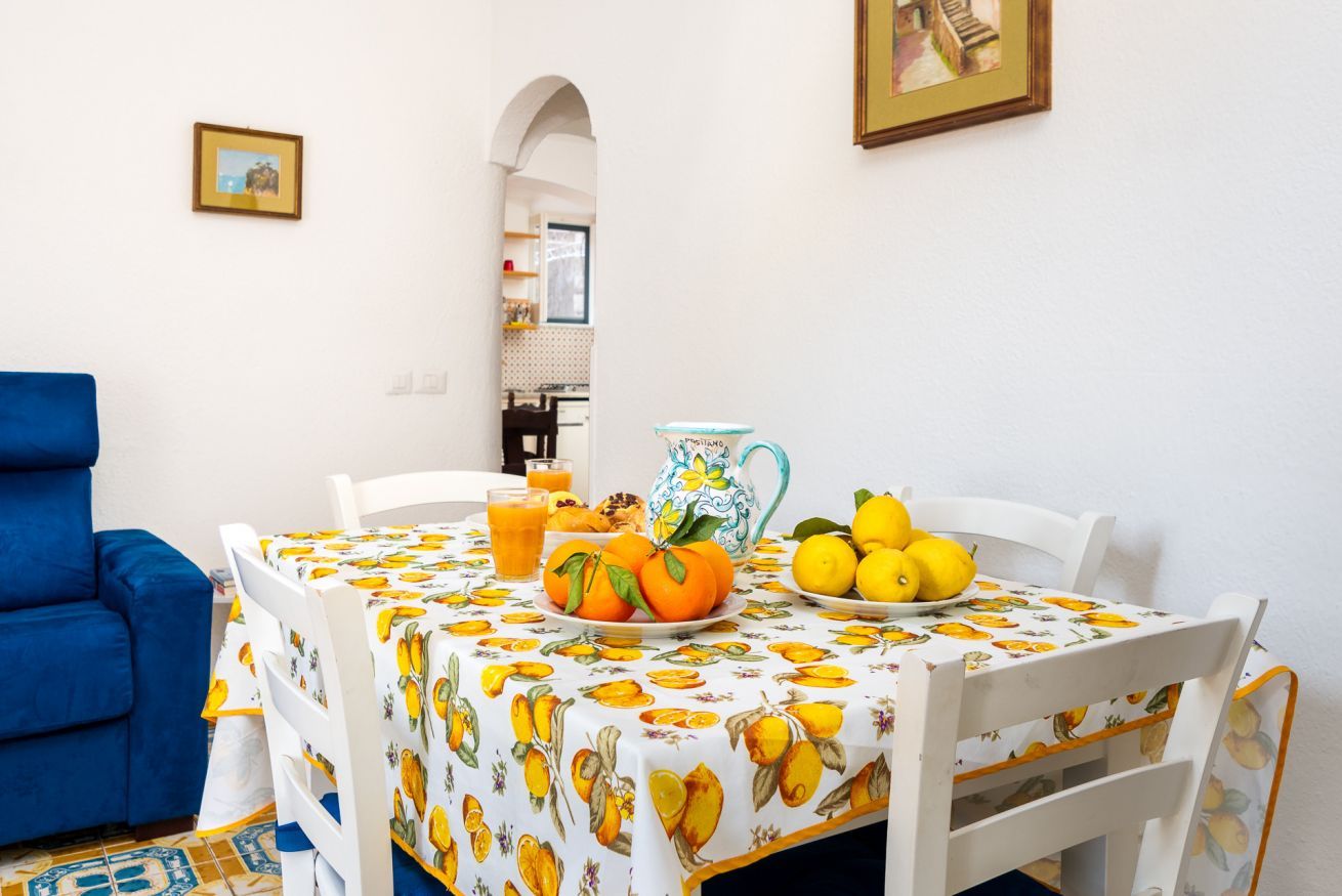 A dining area with a table set for breakfast, featuring a fruit bowl, pitcher, and lemons.