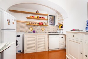 A compact kitchen with a washing machine, a dishwasher, and a stove. - Casa Simona | Independent Home with Private Garden in the Heart of Positano (Positano)