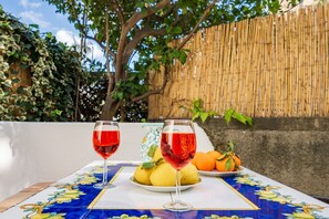 Una mesa con dos copas de vino, un plato de limones y una cesta de naranjas.