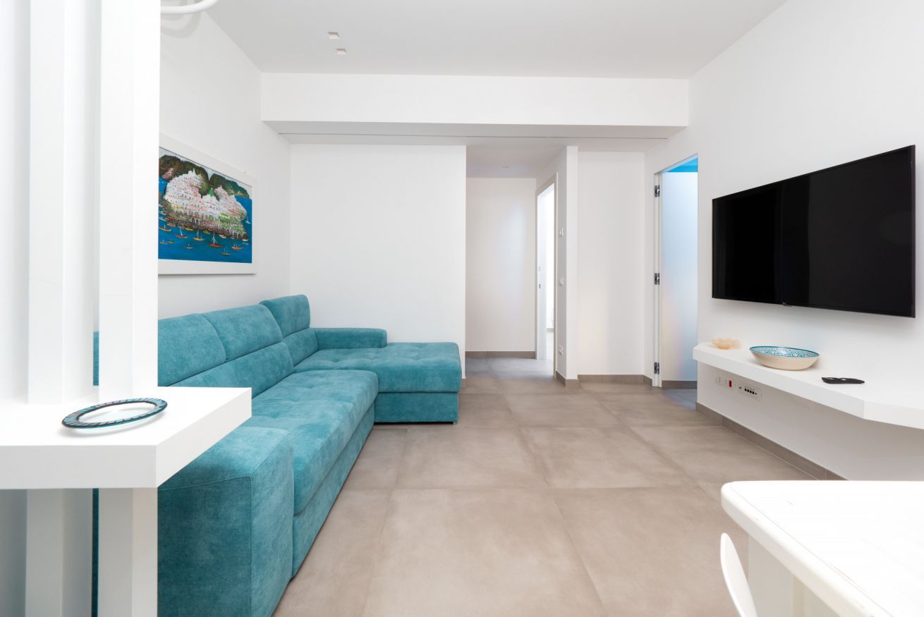 Een moderne woonkamer met een smaragdgroene modulaire bank, een flatscreen televisie aan de muur en een schilderij.