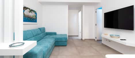 Un salon moderne avec un canapé d’angle turquoise, un téléviseur à écran plat fixé au mur et un tableau accroché au mur.