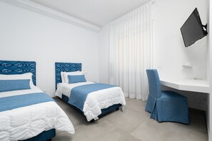 A hotel room with two beds, a desk, and a TV.