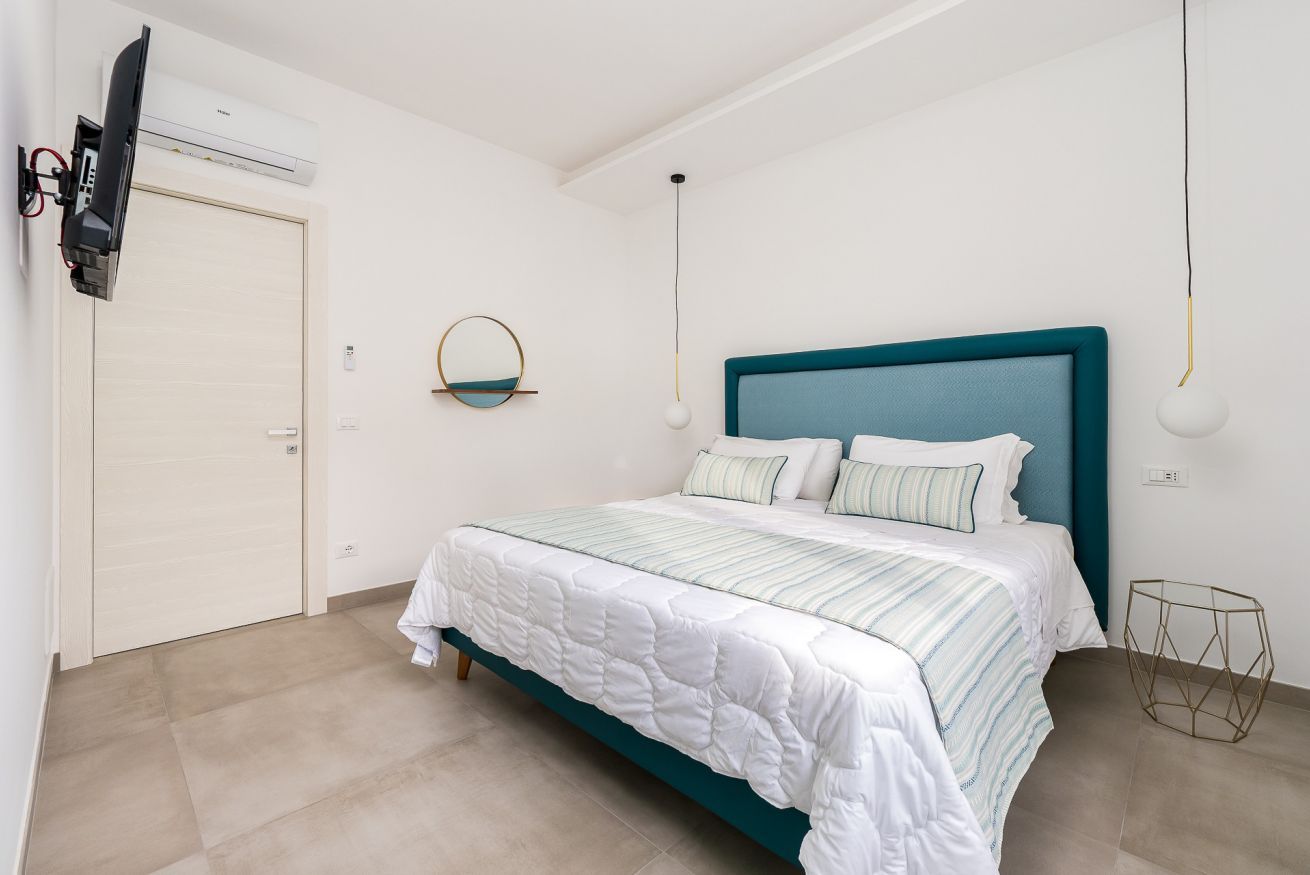 Een slaapkamer met een bed, een aan de muur bevestigde televisie en een plafondventilator.