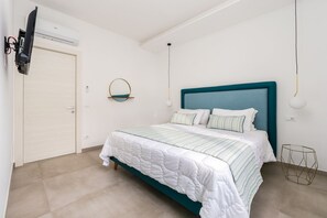 Un dormitori amb un llit, una televisió penjada a la paret i un ventilador de sostre.